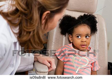 Stock Image - Mid adult doctor talking to young patient. Fotosearch