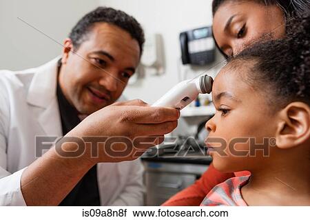 Mid adult doctor using medical equipment on young patient View Large Photo Image Stock Image - Mid adult doctor using medical equipment on young patient. Fotosearch