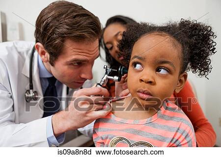 Stock Image - Mid adult doctor using otoscope on patient. Fotosearch