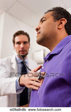 Mid adult doctor using stethoscope on patient View Large Photo Image Stock Image - Mid adult doctor using stethoscope on patient. Fotosearch