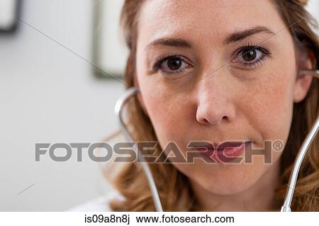 Stock Image - Mid adult doctor wearing stethoscope, portrait. Fotosearch