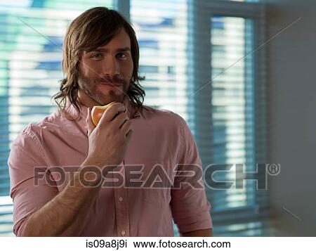 Mid adult man eating apple, portrait View Large Photo Image Stock Image - Mid adult man eating apple, portrait. Fotosearch