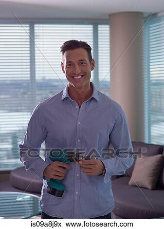 Mid adult man holding hand drill, portrait View Large Photo Image Stock Photo - Mid adult man holding hand drill, portrait. Fotosearch