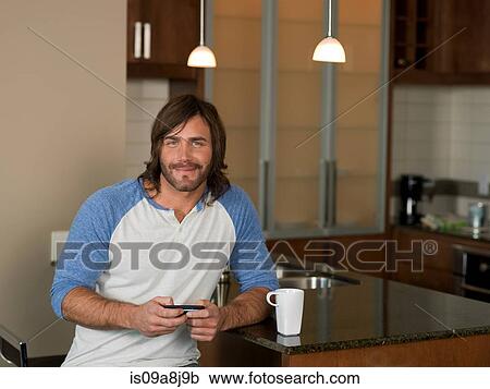 Mid adult man using mobile phone in kitchen, portrait View Large Photo Image Stock Image - Mid adult man using mobile phone in kitchen, portrait. Fotosearch