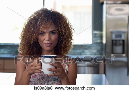 Mid adult woman enjoying coffee in kitchen, portrait View Large Photo Image Stock Photo - Mid adult woman enjoying coffee in kitchen, portrait. Fotosearch