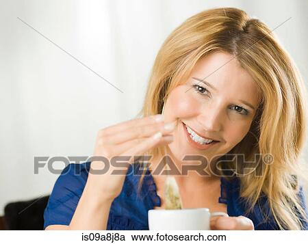Stock Image - Mid adult woman holding cup and smiling, portrait. Fotosearch