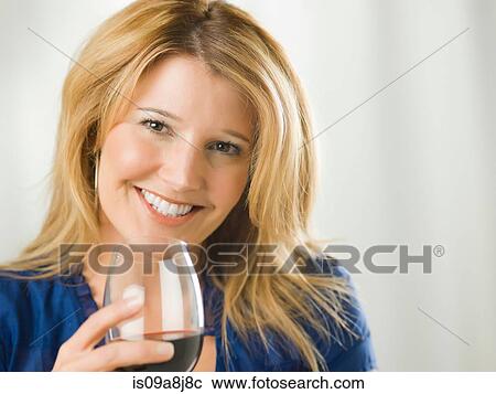Stock Image - Mid adult woman holding glass of wine, portrait. Fotosearch