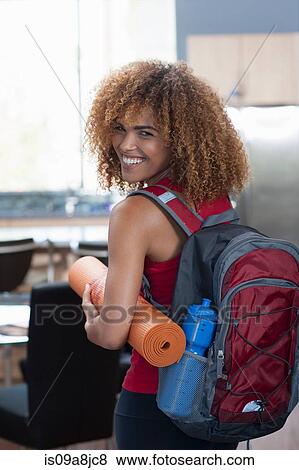 Mid adult woman in carrying yoga mat and rucksack, portrait View Large Photo Image Stock Photo - Mid adult woman in carrying yoga mat and rucksack, portrait. Fotosearch