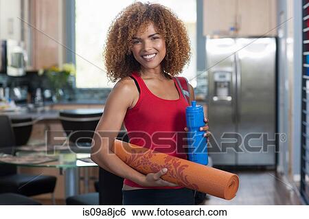 Mid adult woman in holding yoga mat and water bottle, portrait View Large Photo Image Stock Photograph - Mid adult woman in holding yoga mat and water bottle, portrait. Fotosearch
