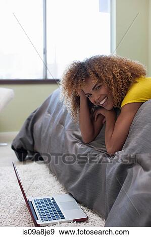 Mid adult woman lying on bed using laptop, portrait View Large Photo Image Stock Photo - Mid adult woman lying on bed using laptop, portrait. Fotosearch