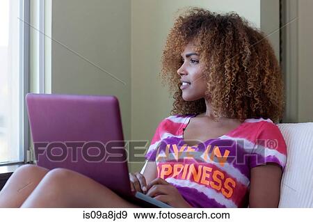 Mid adult woman sitting using laptop, looking away View Large Photo Image Stock Photo - Mid adult woman sitting using laptop, looking away. Fotosearch