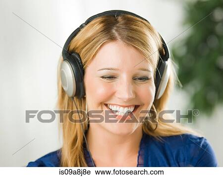 Stock Image - Mid adult woman wearing headphones and smiling. Fotosearch