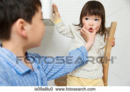Mischievous brother holding young sisters face View Large Photo Image Stock Image - Mischievous brother holding young sisters face. Fotosearch