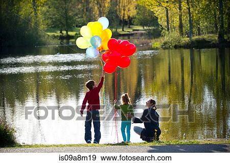 Mother and children in front of lake with bunches of balloons View Large Photo Image Stock Photo - Mother and children in front of lake with bunches of balloons. Fotosearch