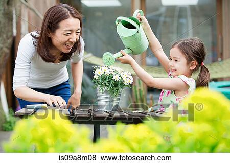 Mother and daughter with toy watering can in garden View Large Photo Image Stock Photo - Mother and daughter with toy watering can in garden. Fotosearch