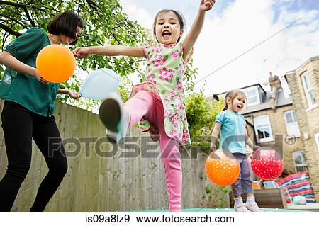 Mother and daughters playing in garden with balloons View Large Photo Image Stock Photo - Mother and daughters playing in garden with balloons. Fotosearch