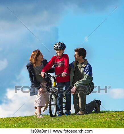 Mother and father encouraging son to ride bicycle View Large Photo Image Stock Image - Mother and father encouraging son to ride bicycle. Fotosearch