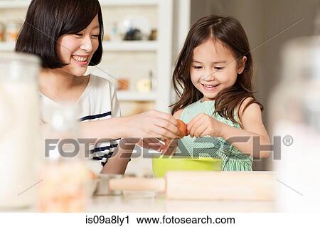 Mother and young daughter cracking egg into mixing bowl View Large Photo Image Stock Image - Mother and young daughter cracking egg into mixing bowl. Fotosearch