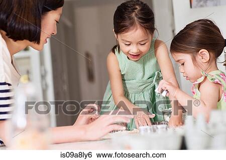 Stock Photograph - Mother and young daughters making pastry. Fotosearch