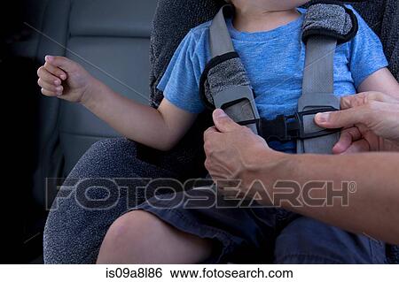 Stock Photograph - Mother fastening child safety seat belt in car. Fotosearch