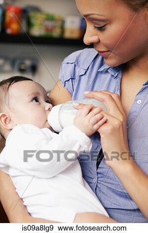 Mother feeding baby girl bottle of milk View Large Photo Image Stock Photo - Mother feeding baby girl bottle of milk. Fotosearch
