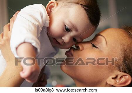 Stock Photo - Mother kissing baby girl's cheek. Fotosearch