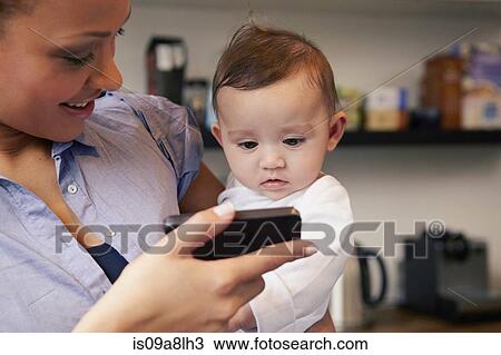Mother showing baby girl smartphone View Large Photo Image Stock Image - Mother showing baby girl smartphone. Fotosearch