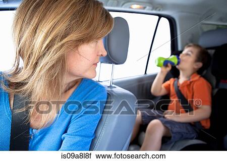 Mother watching boy drink from bottle in back seat of car View Large Photo Image Stock Image - Mother watching boy drink from bottle in back seat of car. Fotosearch