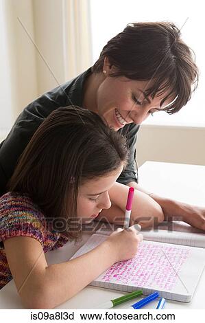 Stock Image - Mother watching daughter writing. Fotosearch