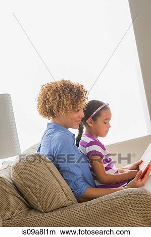 Picture - Mother with daughter reading book. Fotosearch