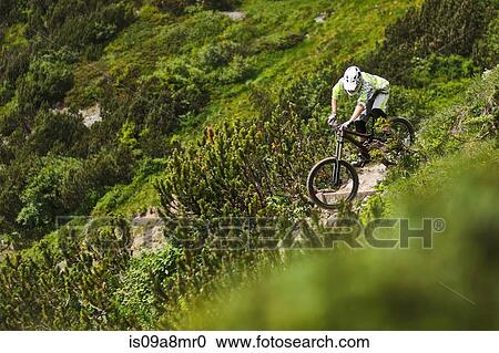 Mountain biker riding down steep hill path View Large Photo Image Stock Image - Mountain biker riding down steep hill path. Fotosearch