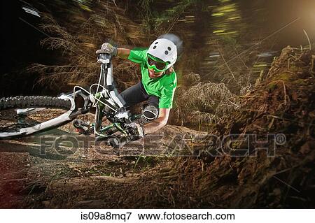 Stock Photo - Mountain biker riding narrow track. Fotosearch