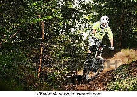 Picture - Mountain biker skidding on forest track. Fotosearch