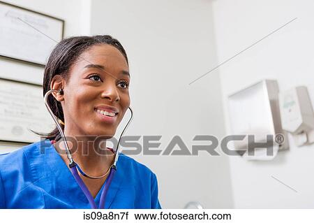 Stock Image - Nurse using stethoscope and smiling. Fotosearch