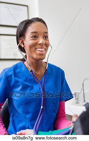 Nurse using stethoscope and smiling View Large Photo Image Stock Image - Nurse using stethoscope and smiling. Fotosearch