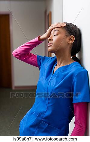 Nurse with eyes closed and hand on head in hospital corridor View Large Photo Image Stock Image - Nurse with eyes closed and hand on head in hospital corridor. Fotosearch