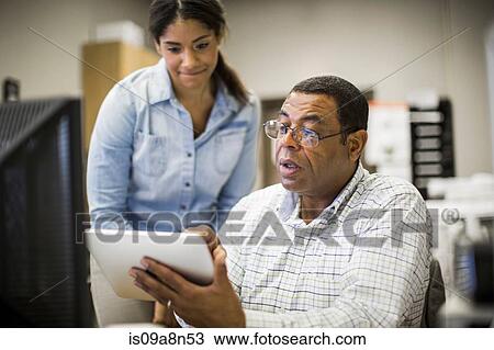 Stock Image - Office colleagues looking at digital tablet. Fotosearch