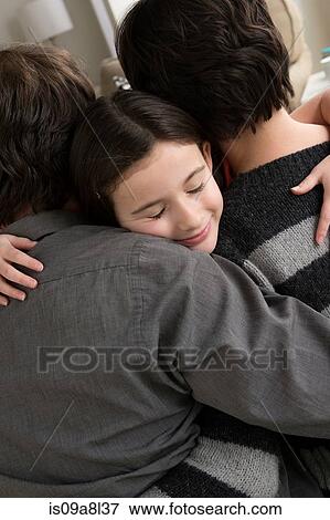 Stock Photo - Parents hugging daughter. Fotosearch