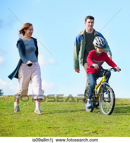 Parents watching son riding bicycle View Large Photo Image Stock Image - Parents watching son riding bicycle. Fotosearch