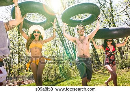 People carrying inner tubes above heads, laughing View Large Photo Image Stock Photo - People carrying inner tubes above heads, laughing. Fotosearch