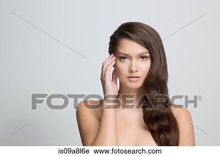 Stock Image - Portrait of brunette woman touching face. Fotosearch