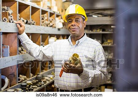 Portrait of man in plumbing stockroom holding products View Large Photo Image Stock Photograph - Portrait of man in plumbing stockroom holding products. Fotosearch
