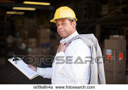 Stock Image - Portrait of man in warehouse with clipboard. Fotosearch