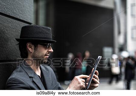 Stock Photo - Portrait of man using digital tablet on city street. Fotosearch