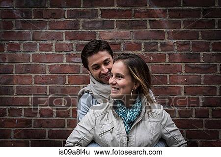 Portrait of smiling couple in front of brick wall View Large Photo Image Stock Photograph - Portrait of smiling couple in front of brick wall. Fotosearch