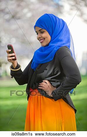 Portrait of young female in park looking at her mobile phone View Large Photo Image Stock Photograph - Portrait of young female in park looking at her mobile phone. Fotosearch