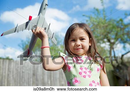 Portrait of young girl in garden holding toy airplane View Large Photo Image Stock Image - Portrait of young girl in garden holding toy airplane. Fotosearch
