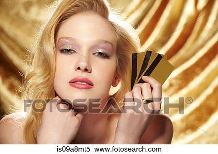 Stock Photography - Portrait of young woman holding gold credit cards. Fotosearch