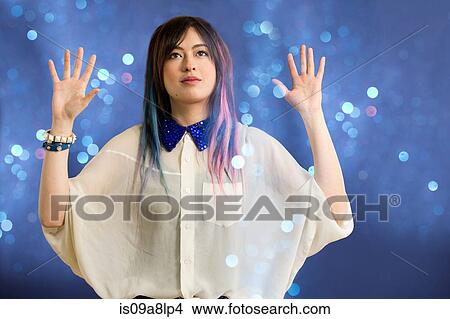 Portrait of young woman with arms up looking at glitter View Large Photo Image Picture - Portrait of young woman with arms up looking at glitter. Fotosearch