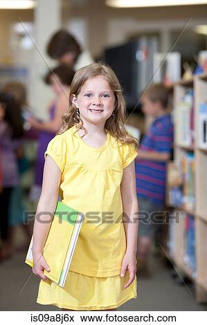 Schoolgirl holding book in library and smiling, portrait View Large Photo Image Stock Photo - Schoolgirl holding book in library and smiling, portrait. Fotosearch